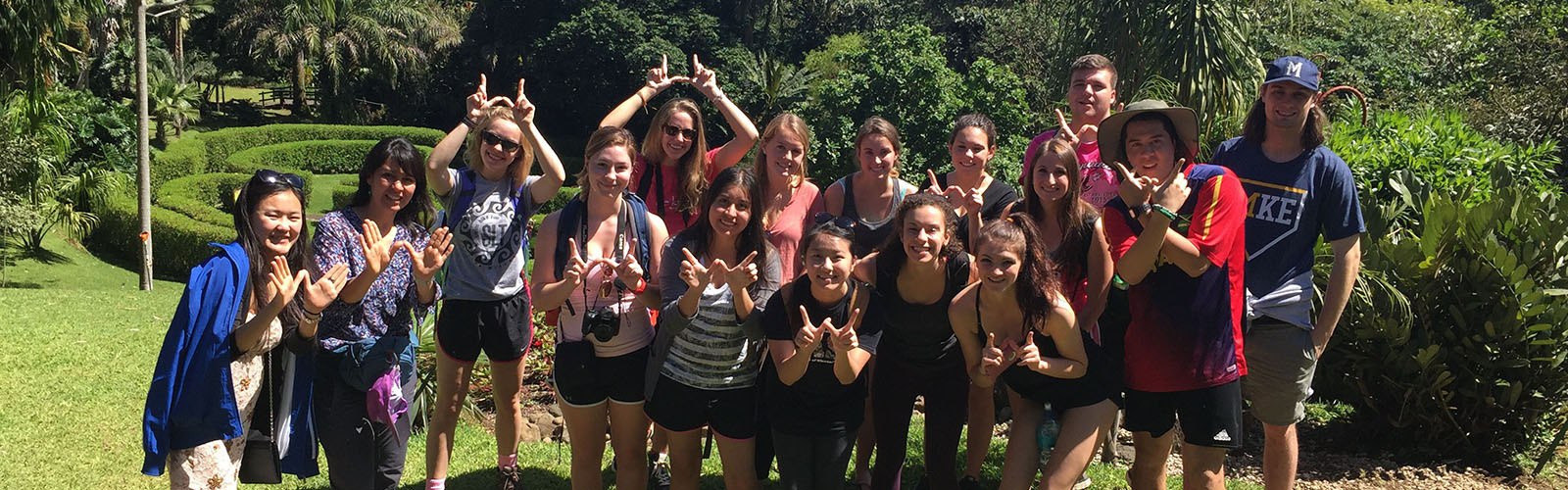A group of students are posed together and making the "W" sign with their hands. They are smiling at the camera.